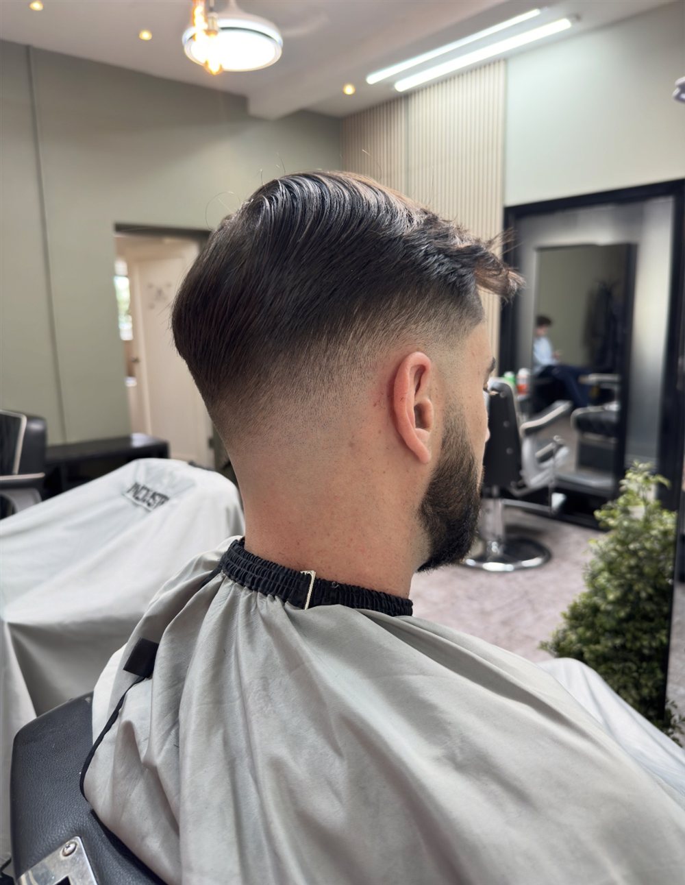 Side view of a low fade with a swept-back top and a full beard