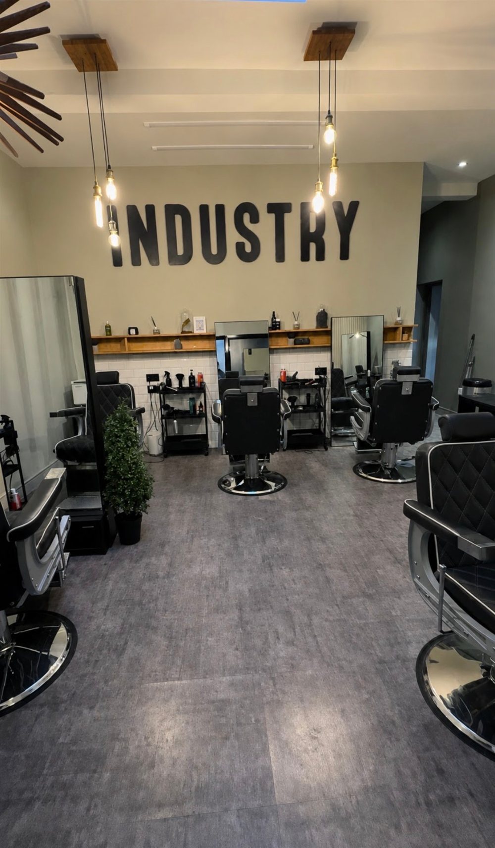 The shop floor with barber chairs beneath the Industry wall sign